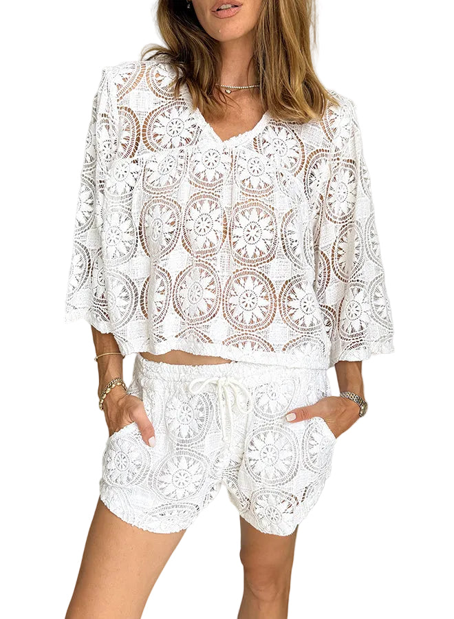 Woman wearing a white lace outfit against a neutral background