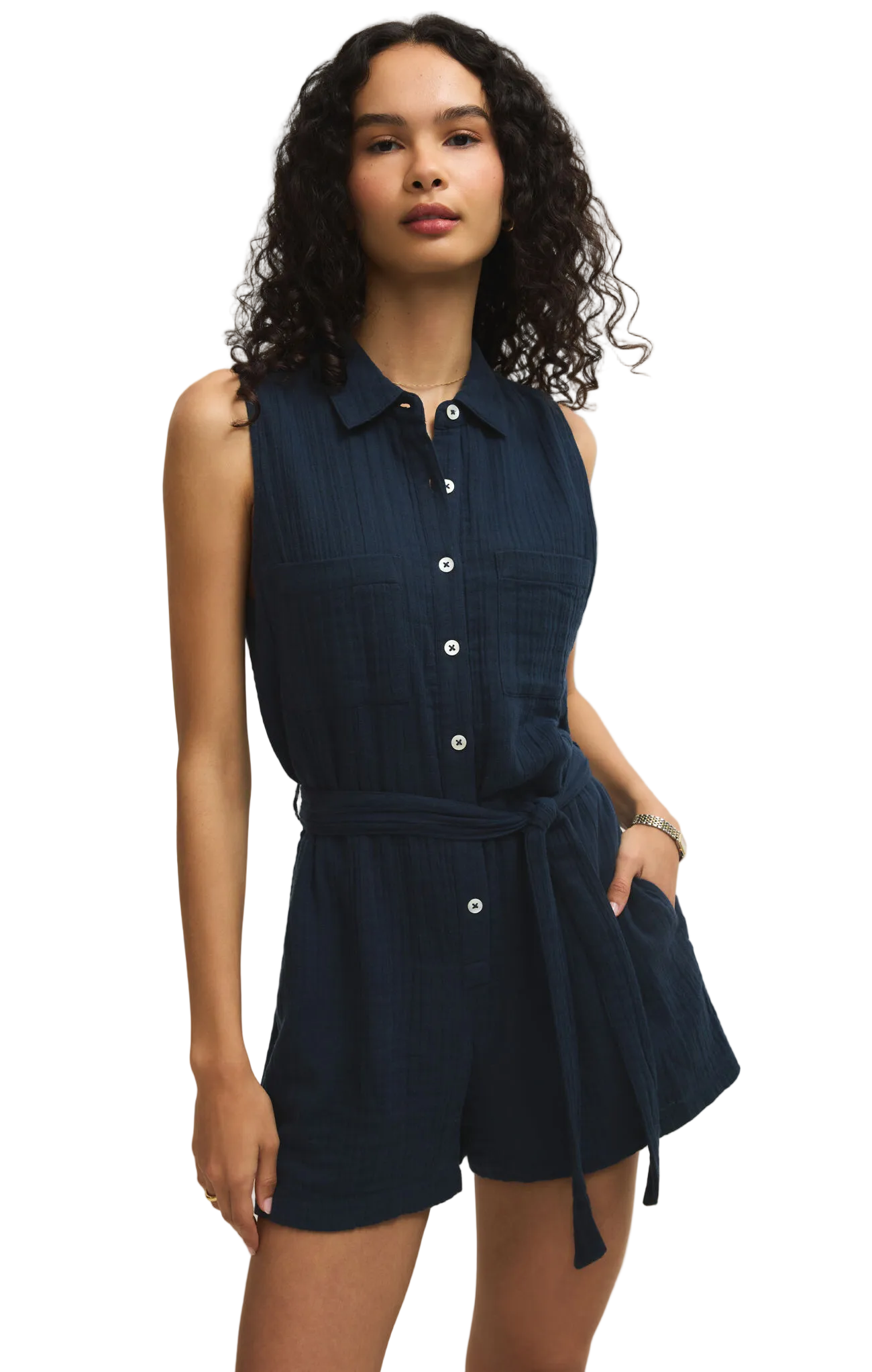 Woman wearing a navy sleeveless shirt dress against a beige background